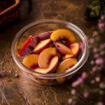 Angle view of frozen peaches in a glass circular container.