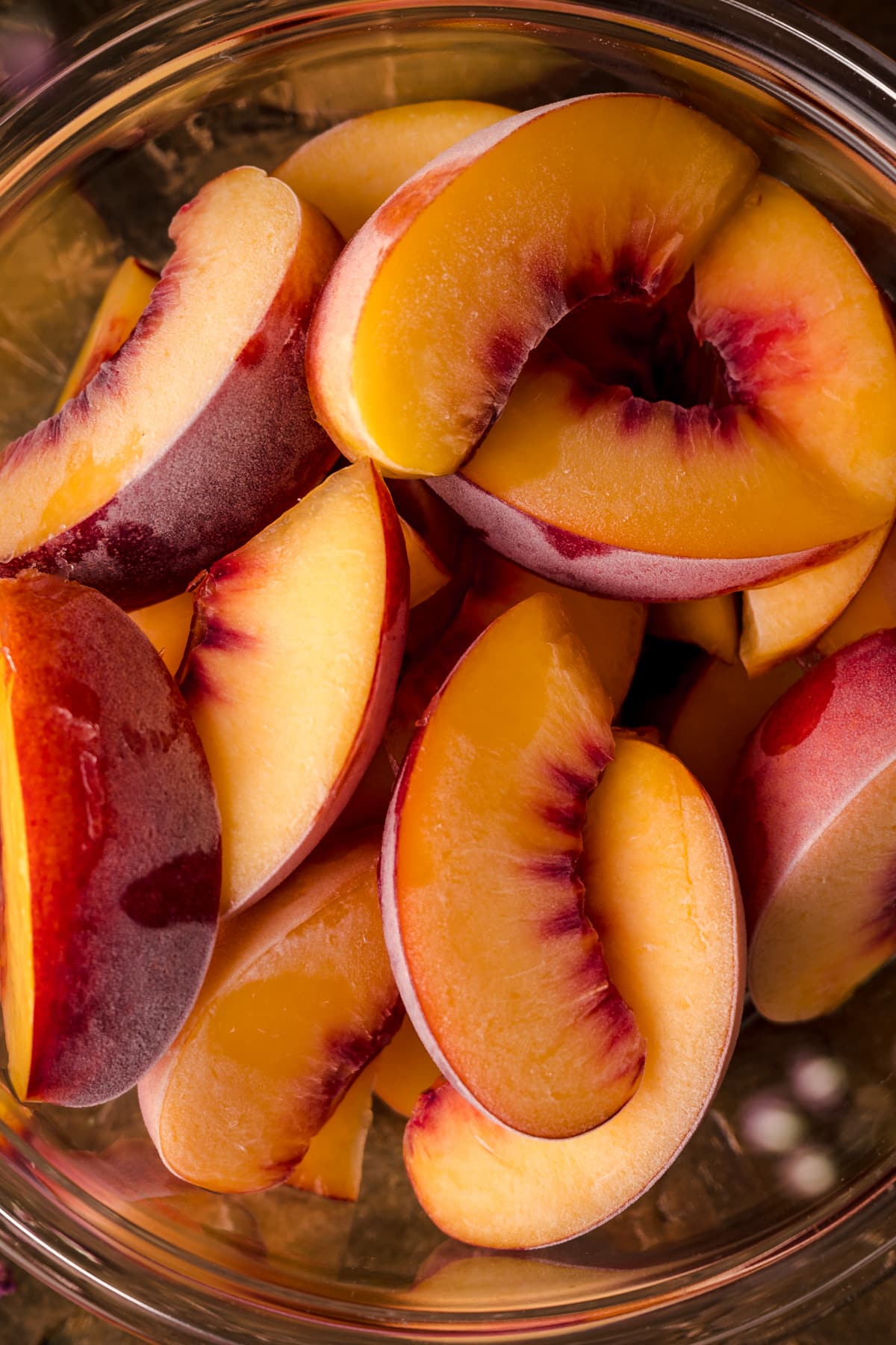 Flat lay image of frozen peaches with sprigs of tiny flowers near by.