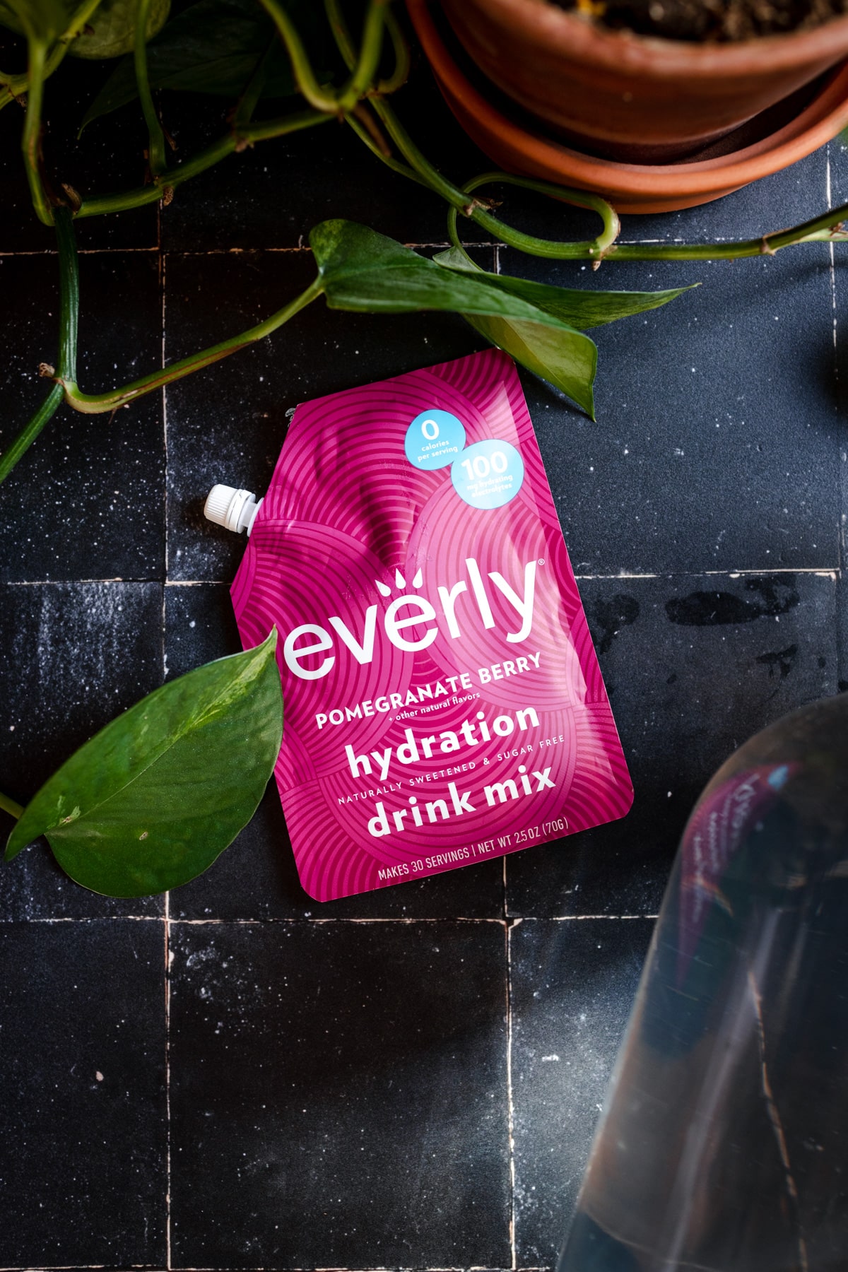Pink packet of pomegranate flavored hydration packet on a black tile surface.