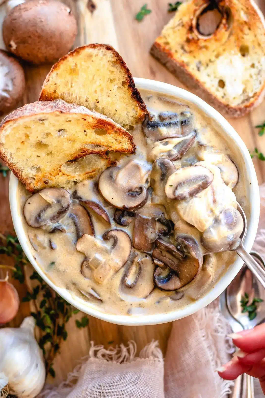 Full bowl of cream of mushroom soup with toasted bread on top.
