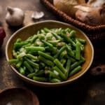 Cooked green beans from a can with sautéed onion garlic and spices.