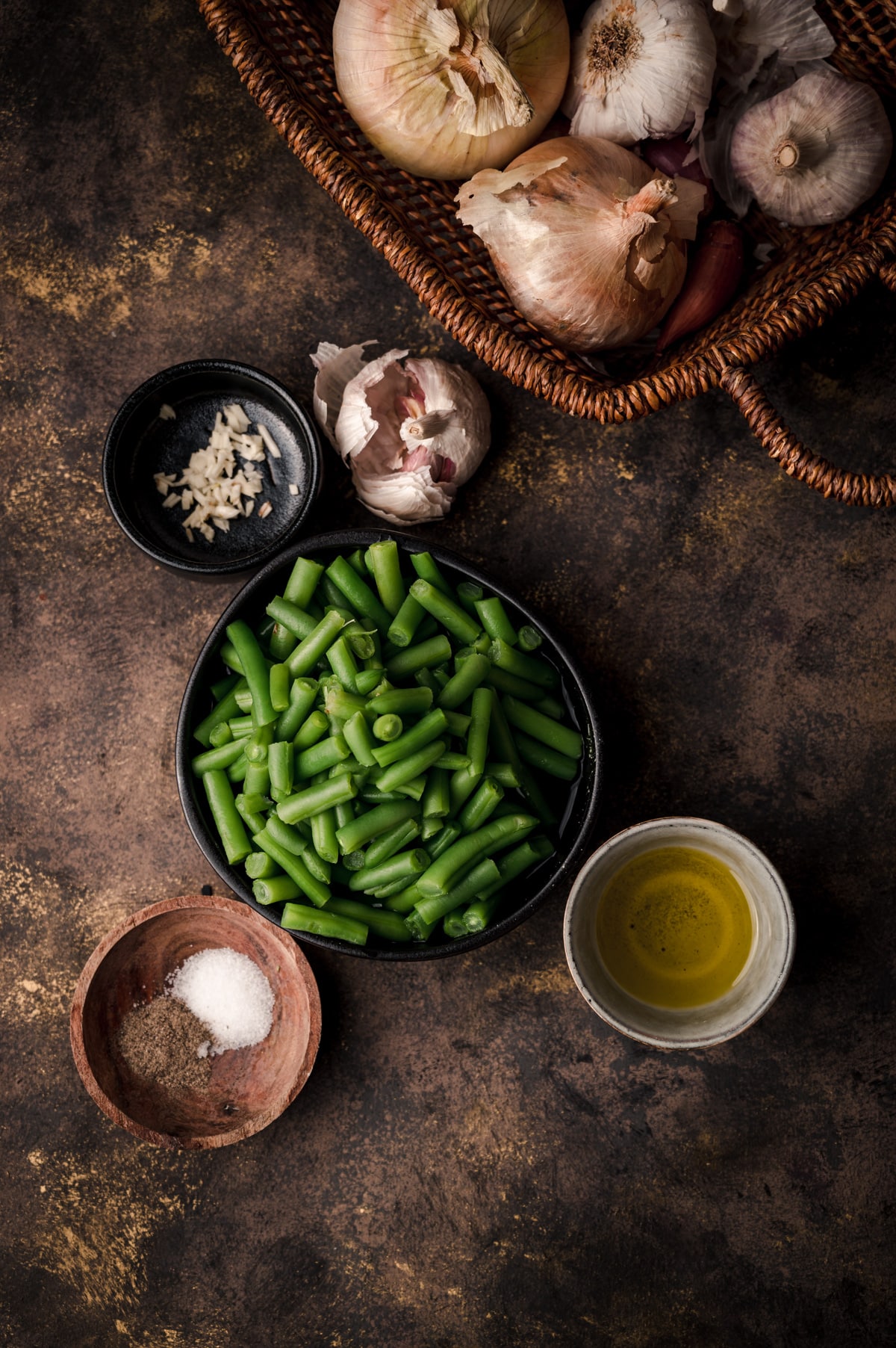 Bowl of canned green beans with ingredients in small bowls surrounding it.