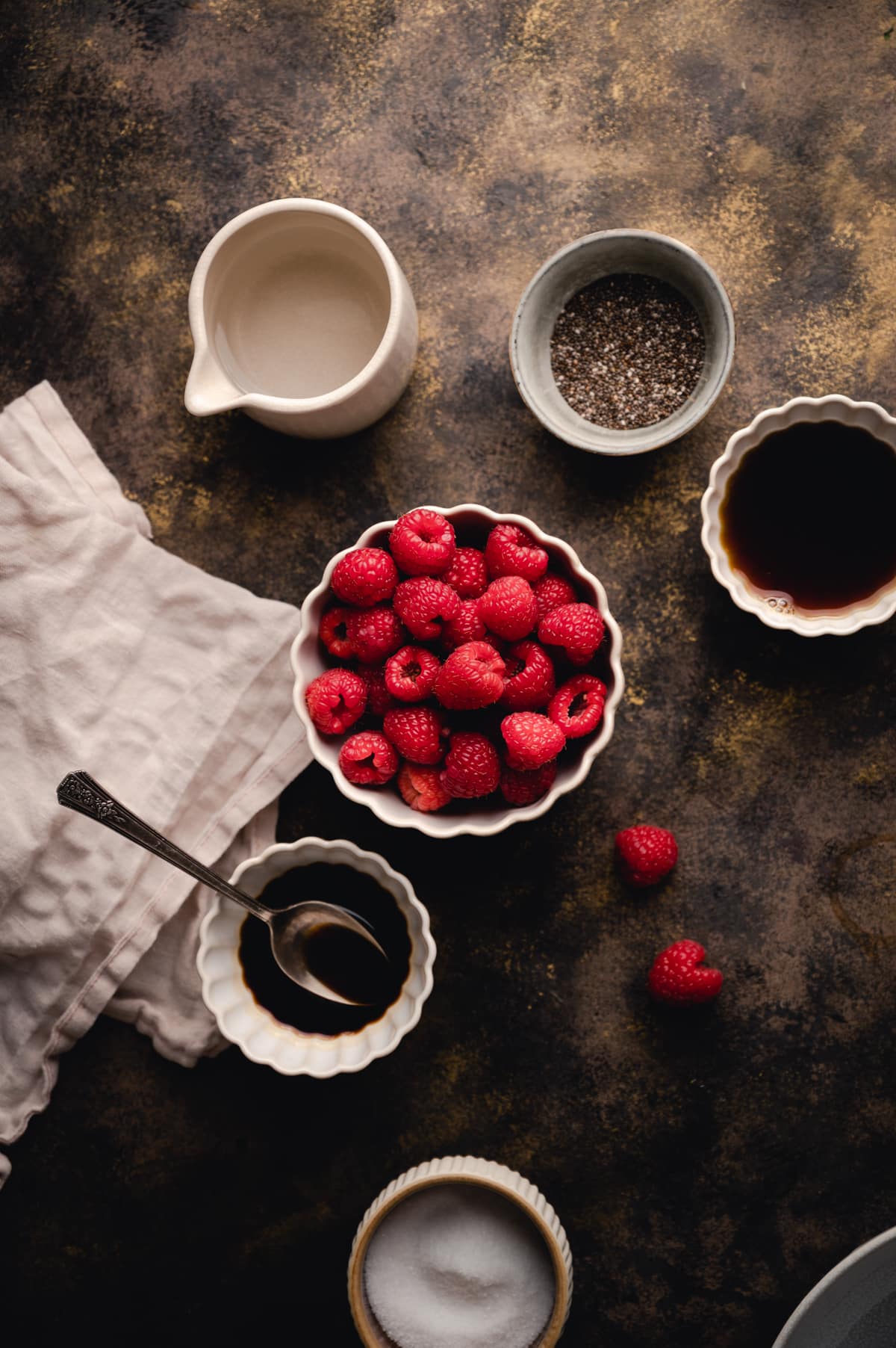 Bowls of ingredients including chia seeds, raspberries, maple syrup, and more.