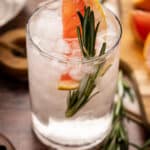 Refreshing grapfruit infused water with a fresh sprig of rosemary and pink grapefruit sticking out of the glass.