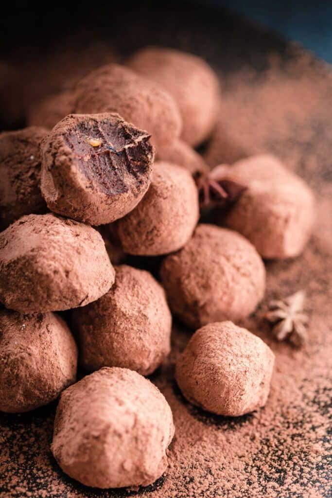 Decadent chocolate date balls in a pile, coated in cocoa powder.
