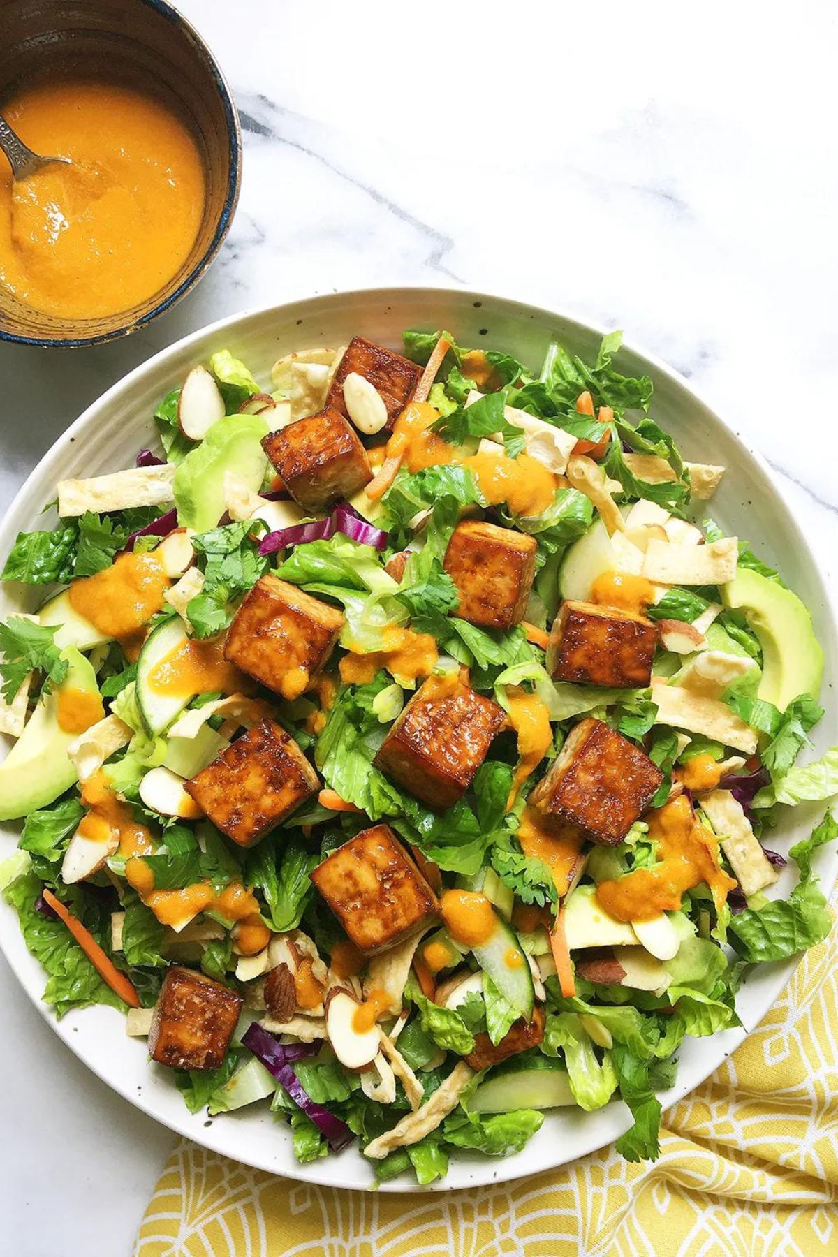 A vegan salad with tofu and avocado on a plate.