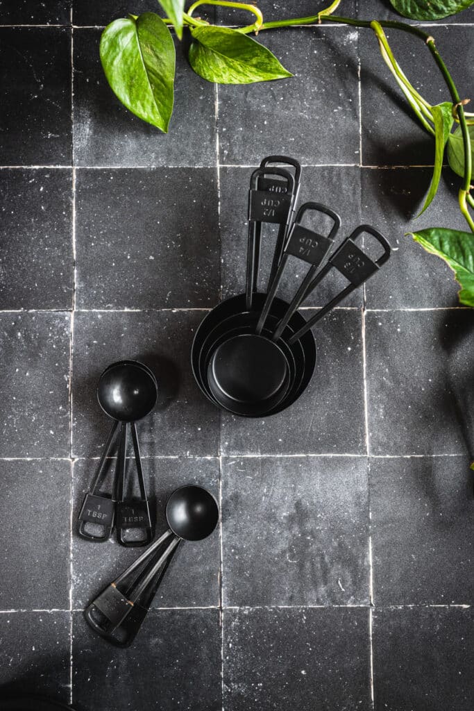 Black measuring cups and spoons on black tile.