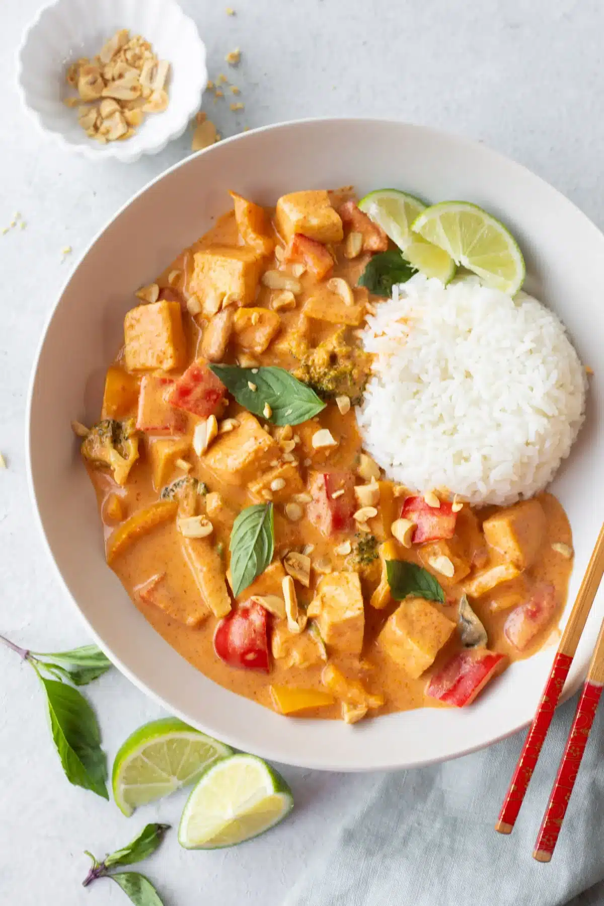 Vegan Thai tofu curry served with rice and chopsticks in a white bowl.