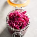 Glass jar with orange rubber ring filled with pickled red cabbage.