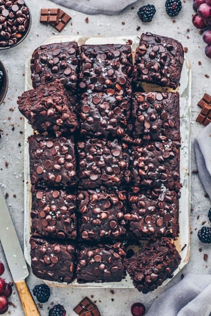 Tray of 15 vegan zucchini brownies with tons of chocolate chips on top. 