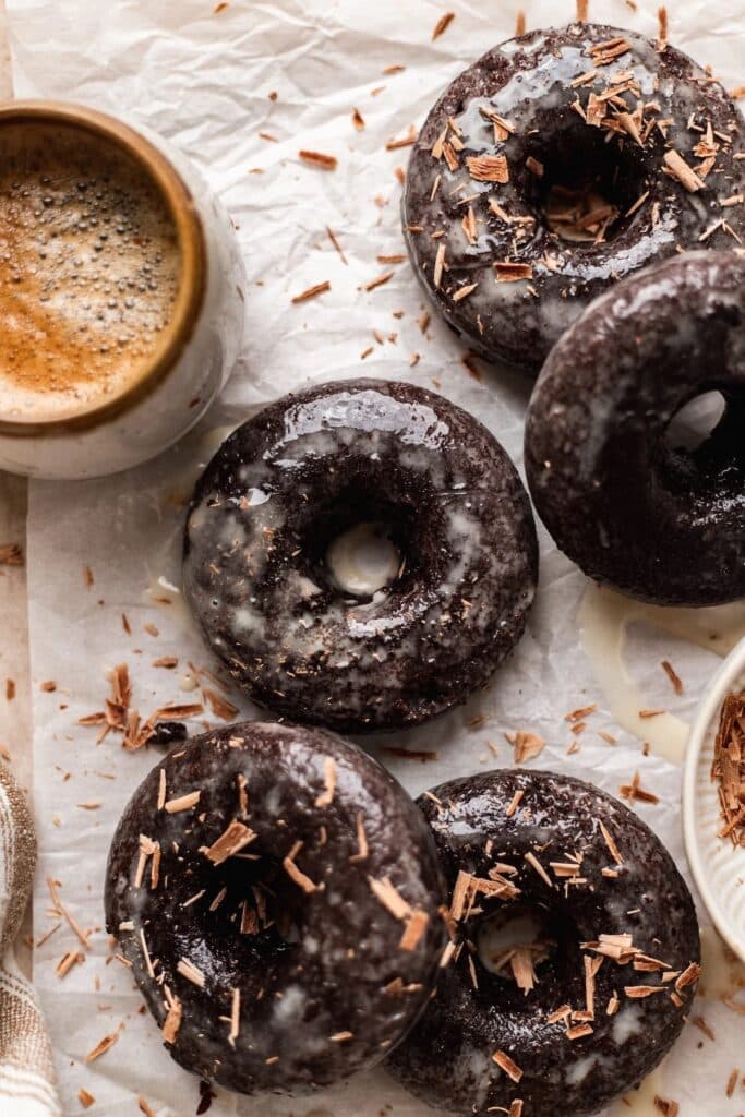 Several chocolate donuts dipped in chocolate glaze with shaved chocolate on top.