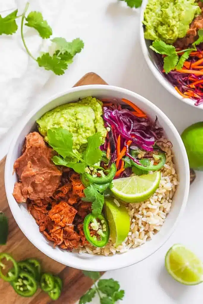 Large bowl filled with bbq jackfruit, refried beans, avocado, rice, and veggies.