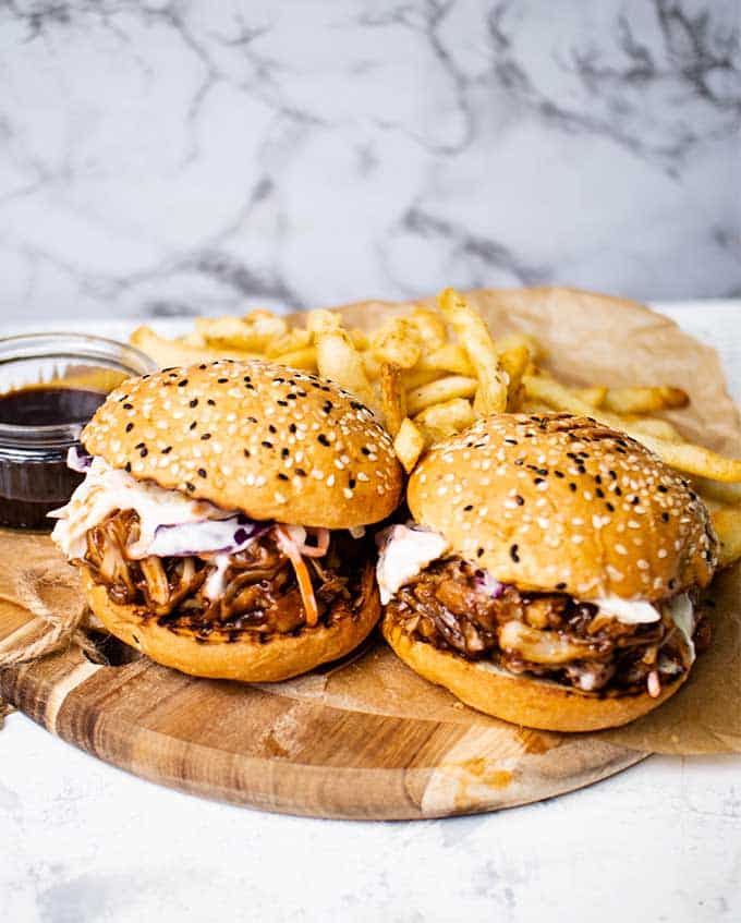 BBQ jackfruit pulled pork smothered in sauce on a bun with fries.