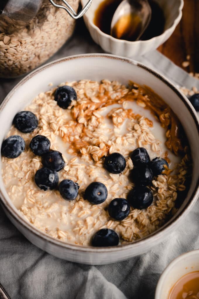 Close up of a bowl of oatmeal with blueberries on top and nut butter swirled in.
