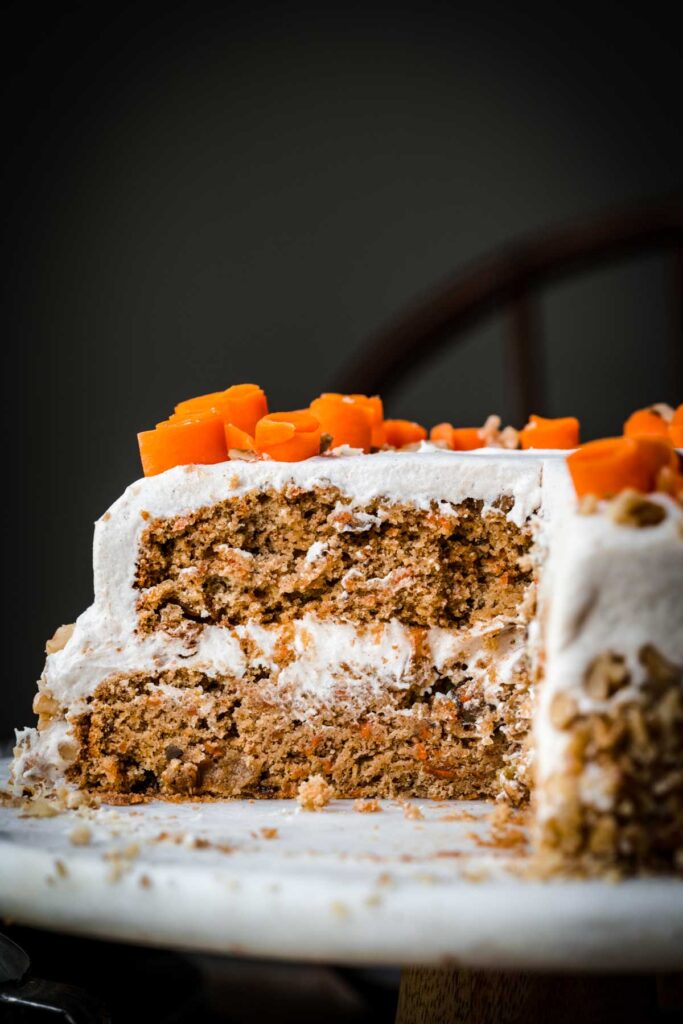Two layer carrot cake with pieces cut out.