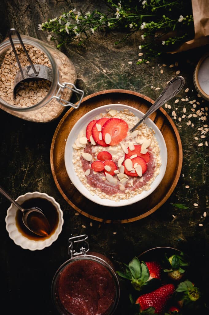 Single-serve oatmeal recipe with strawberry chia jam and sliced strawberries on top.