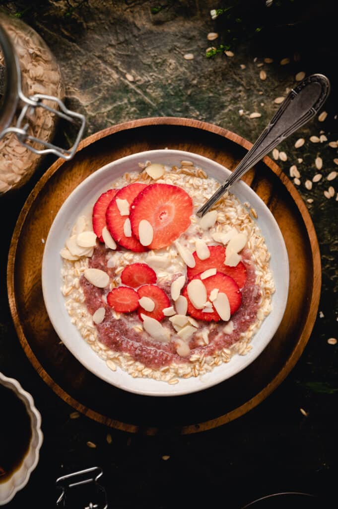 Large white bowl filled with classic oatmeal breakfast with a spoon sticking out.