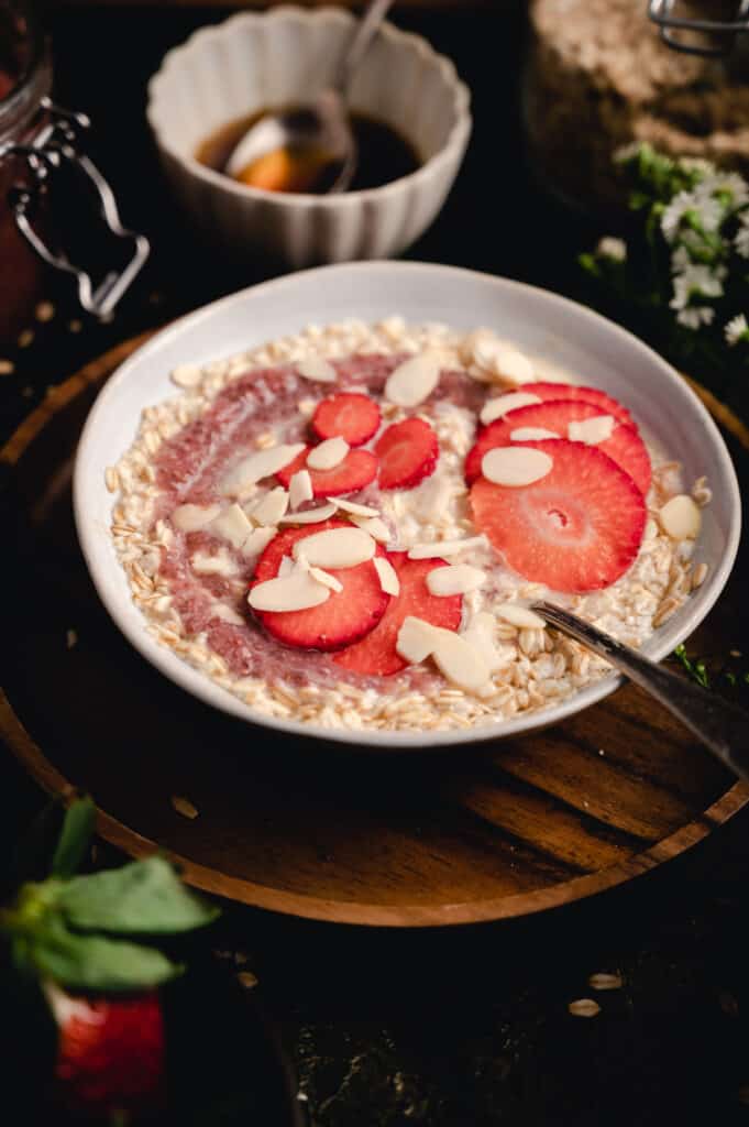 Oatmeal breakfast in a white bowl on a wooden tray.