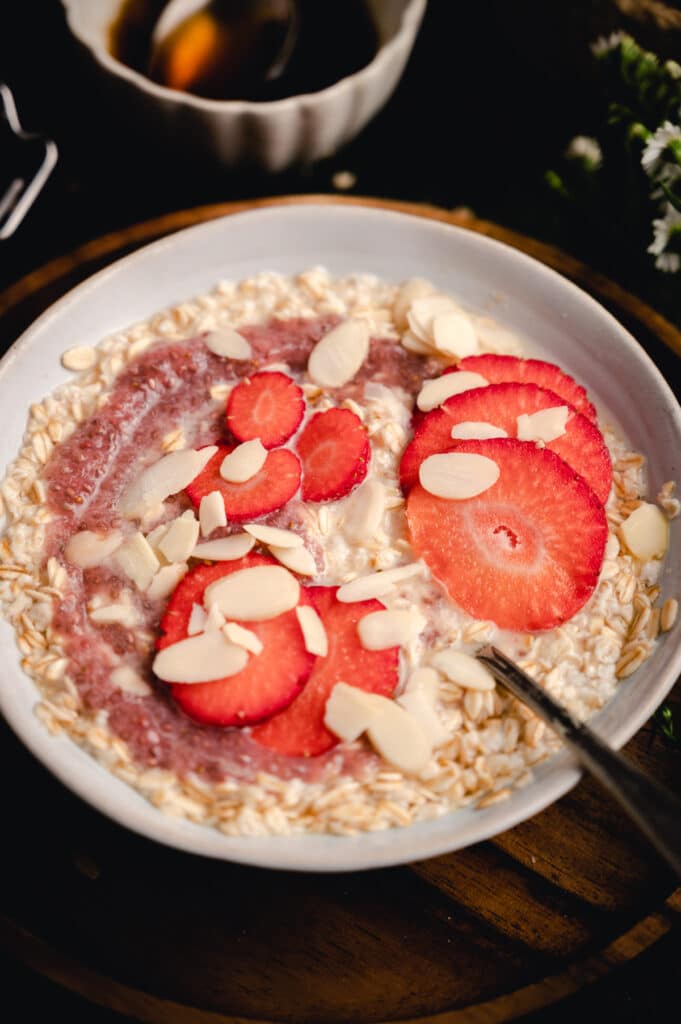 Angle shot of classic oatmeal with sliced strawberries on top.