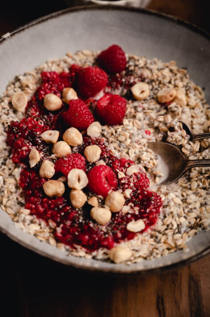 Close up of chia oatmeal topped with hazel nuts, raspberries, and chia jam.