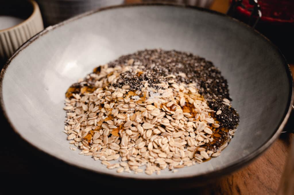 Bowl of rolled oats with maple syrup, salt, chia seeds, on top.