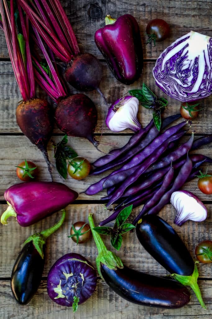 Purple vegetables and fruits on a wooden table.