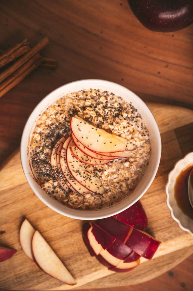 Flatylay photo of apple cinnamon oatmeal with sliced apples fanned out on top.