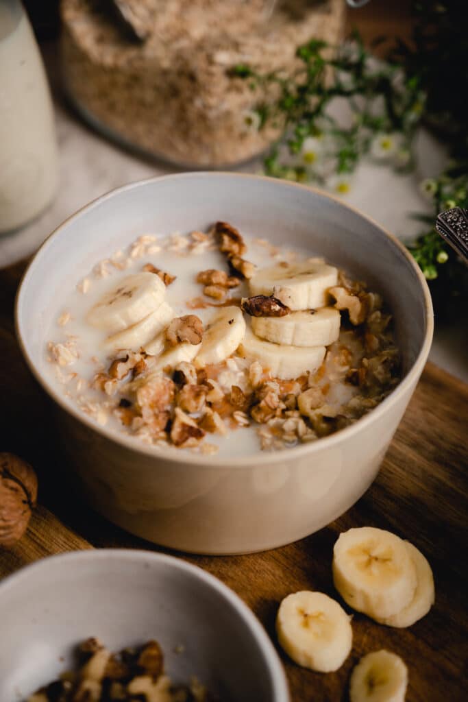 Close up of banana rolled oats oatmeal topped with sliced bananas, oat milk.