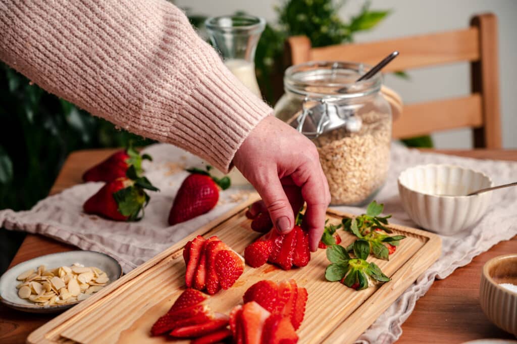 Woman slicing strawberries for homemade oatmeal.
