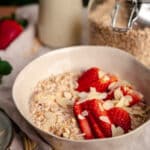 Close up of strawberry rolled oats with sliced strawberries and slivered almonds on top.