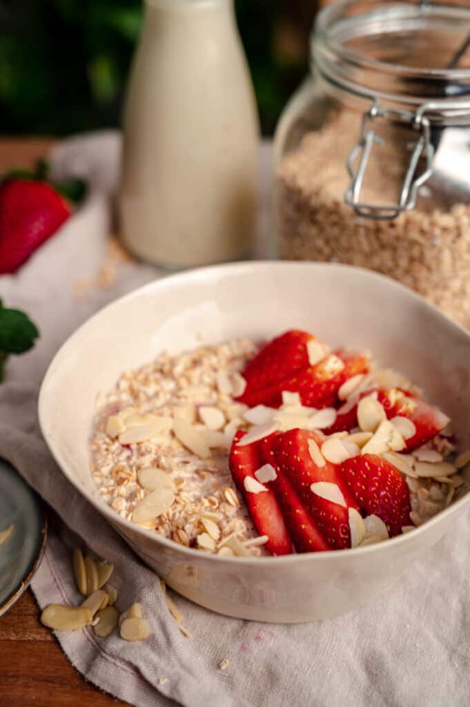Close up of strawberry rolled oats with sliced strawberries and slivered almonds on top.