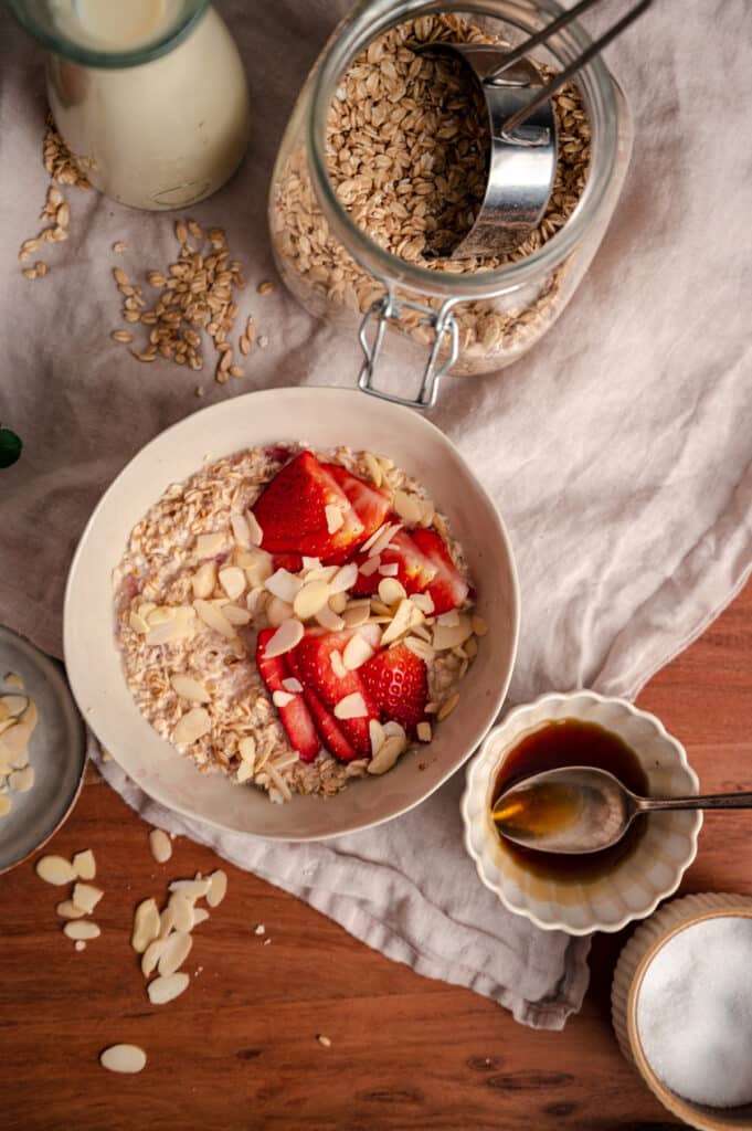 Flatlay photo of old fashioned oatmeal on a linen napkin with a jar of oats.