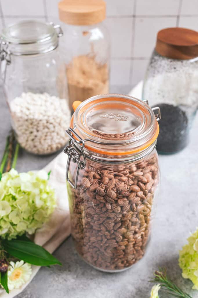 1/2 gal mason jar filled with pinto beans on a gray table.