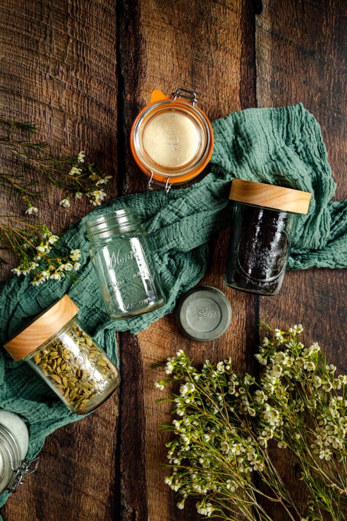 Pint sized mason jars filled with ingredients with one empty in the middle laying on its back.