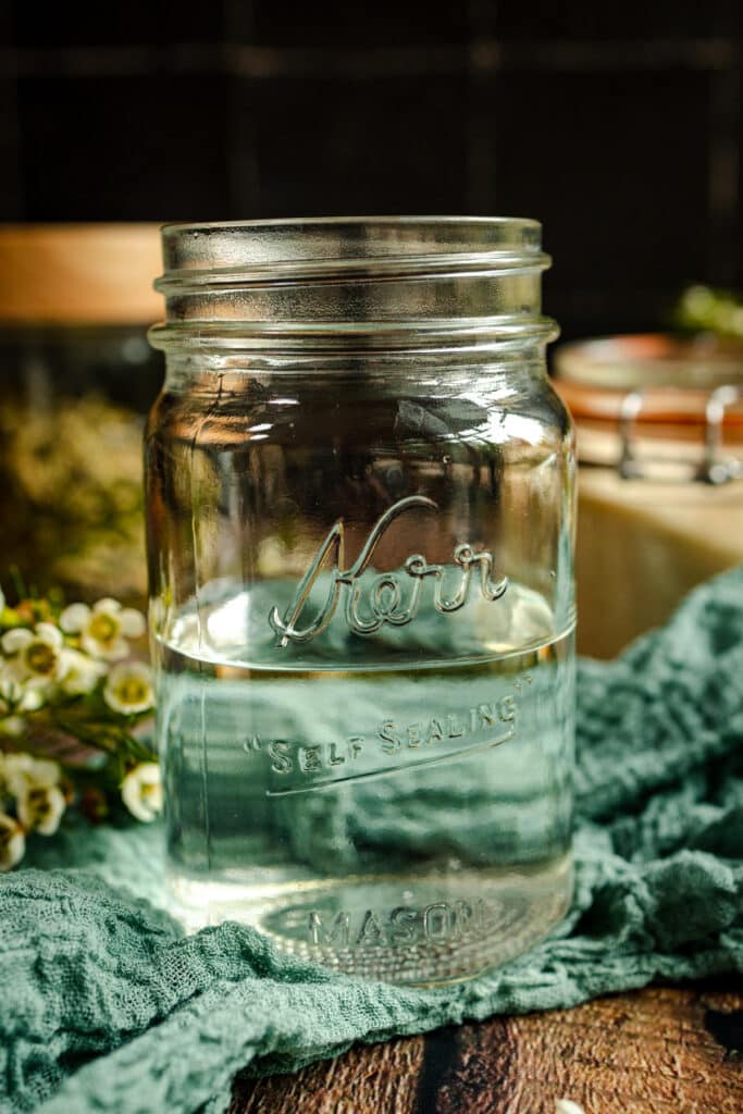 Close up of pint sized glass jar half filled with water.