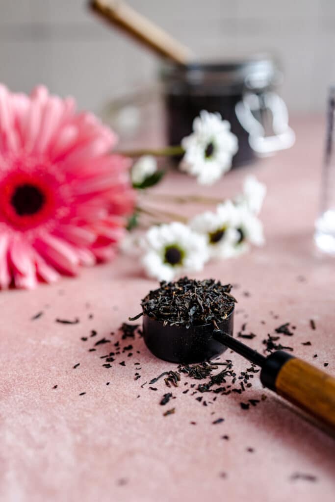 Bright pink flower with a tablespoon overflowing with black tea.