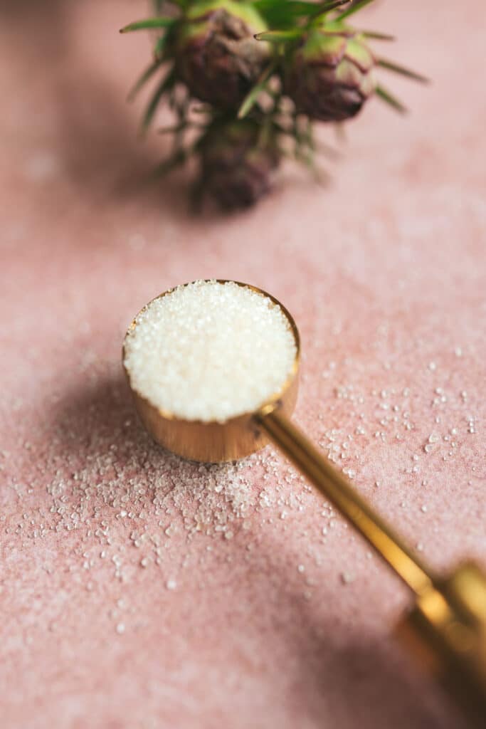 Close up of golden teaspoon filled with raw cane sugar.