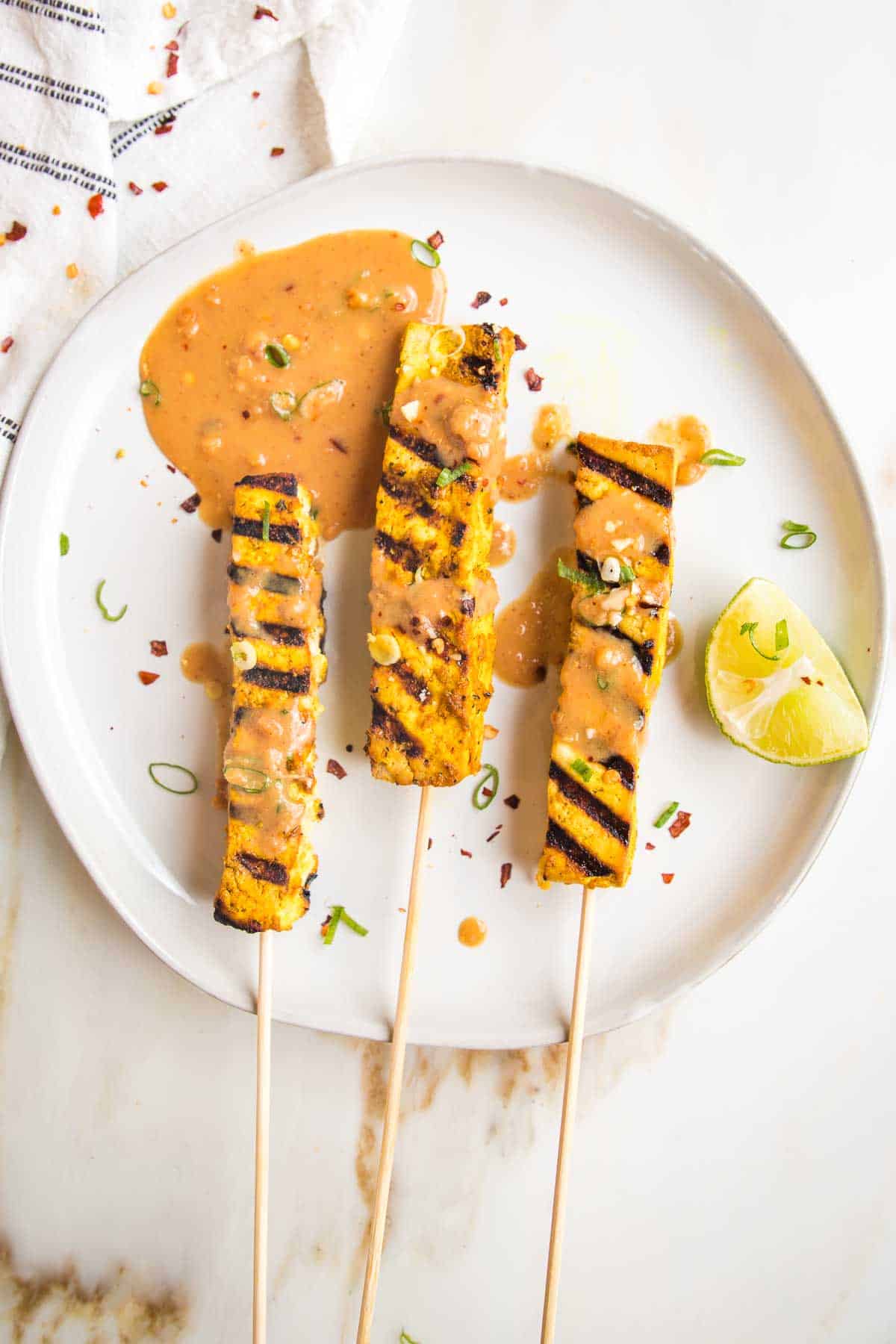 Vegan grilled tofu corn skewers with sauce on a plate.