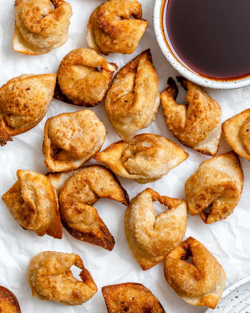 A plate of vegan fried dumplings with tofu filling and dipping sauce.