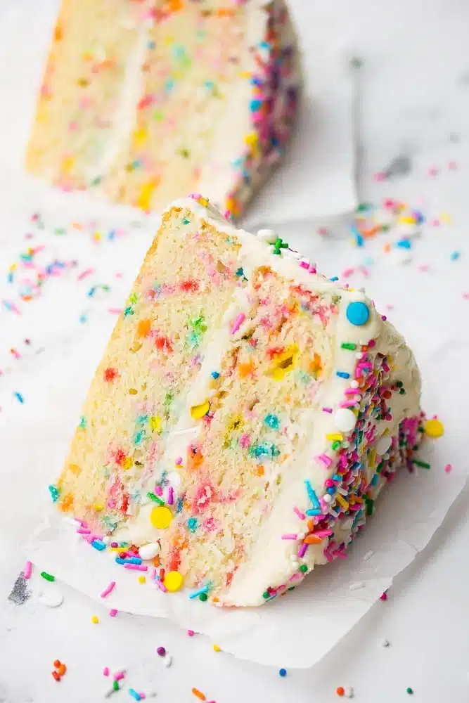 two slices of vegan funfetti cake with sprinkles on the table