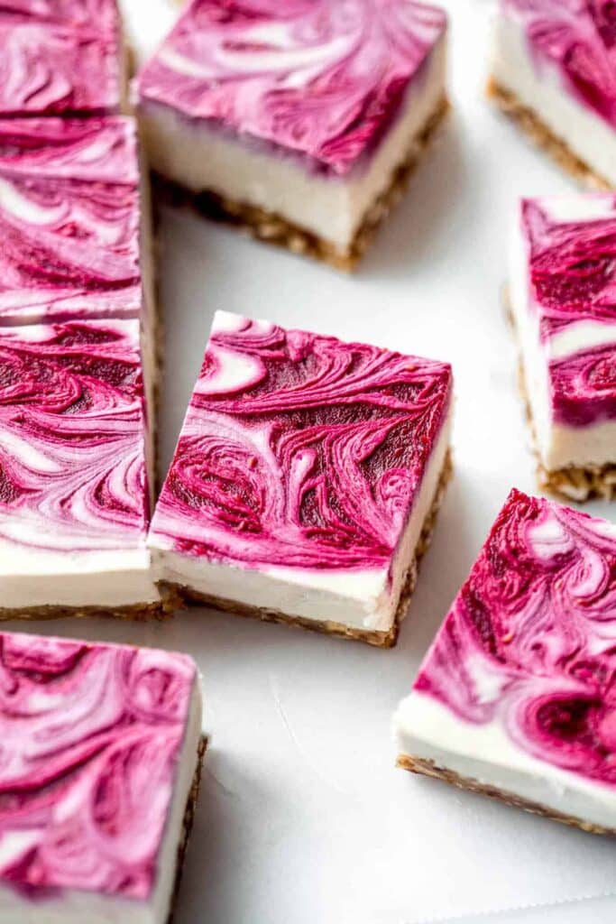 Bars of raspberry cheesecake with a vibrant pink swirl on top.
