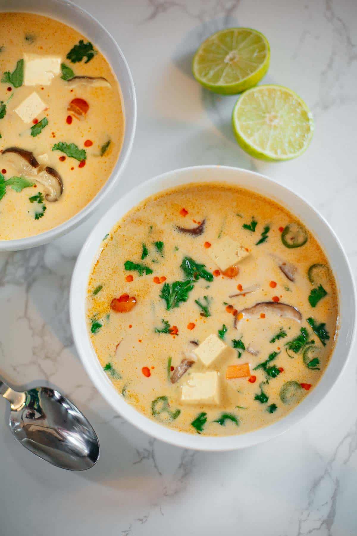 Two white bowls filled with coconut Thai soup.