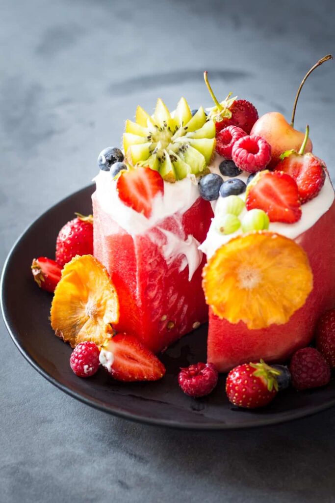 Fresh watermelon with rind cut off and topped with coconut cream and fresh fruit.