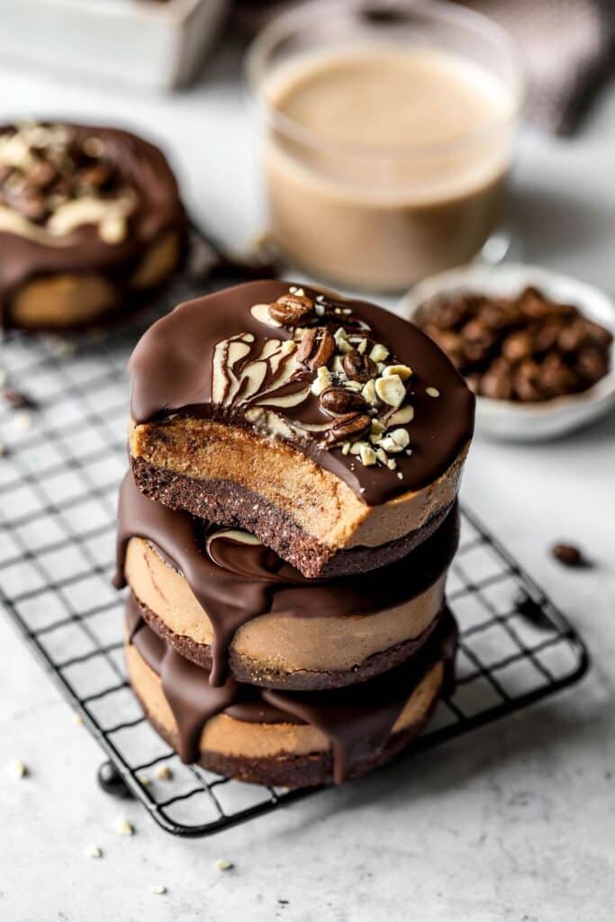 Personal-sized vegan coffee cheesecake stacked on top of each other and topped with chocolate. 