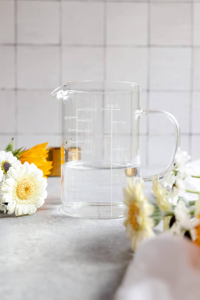Clear glass liquid measuring cup filled to the cup line.