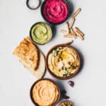 Chickpea hummus, herbs hummus, beetroot hummus and lentils humus with bread sticks and fresh bread.