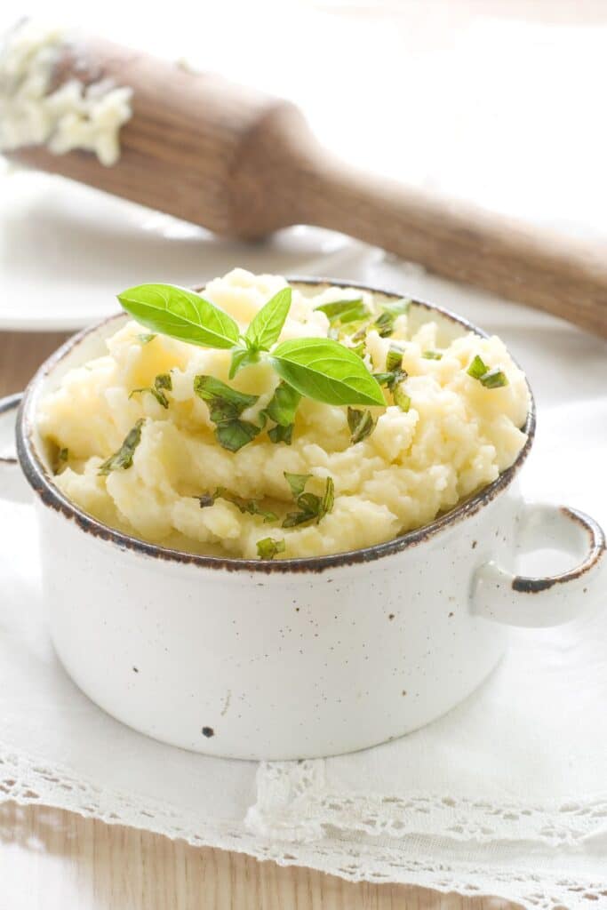 Two handled bowl filled with mashed potatoes.