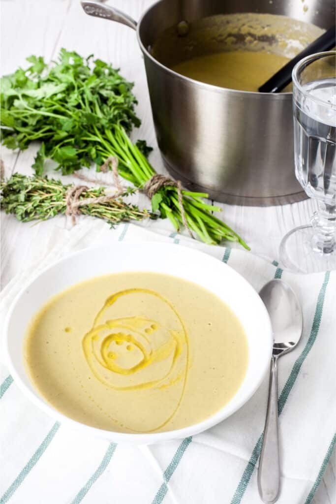 White ceramic bowl filled with potato leek soup with olive oil swirl. 