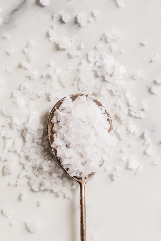 Spoon overflowing with white flake salt. 