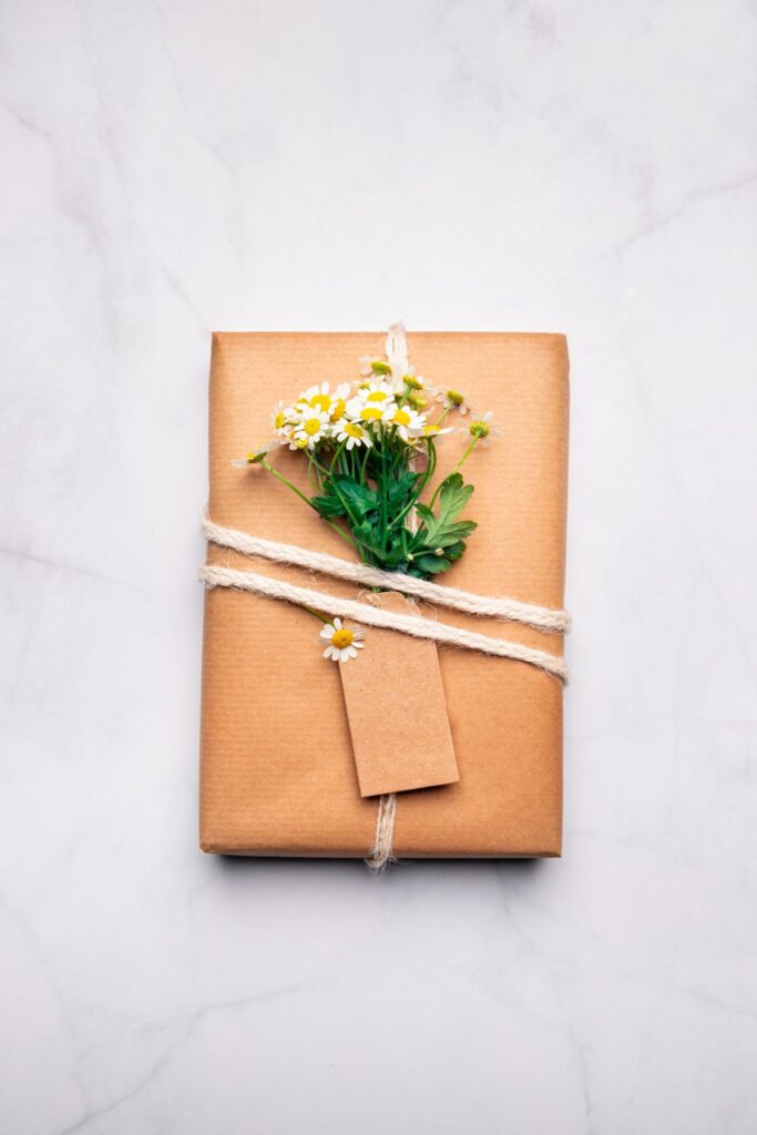 Holiday gift wrapped in kraft paper with fresh flowers on top.